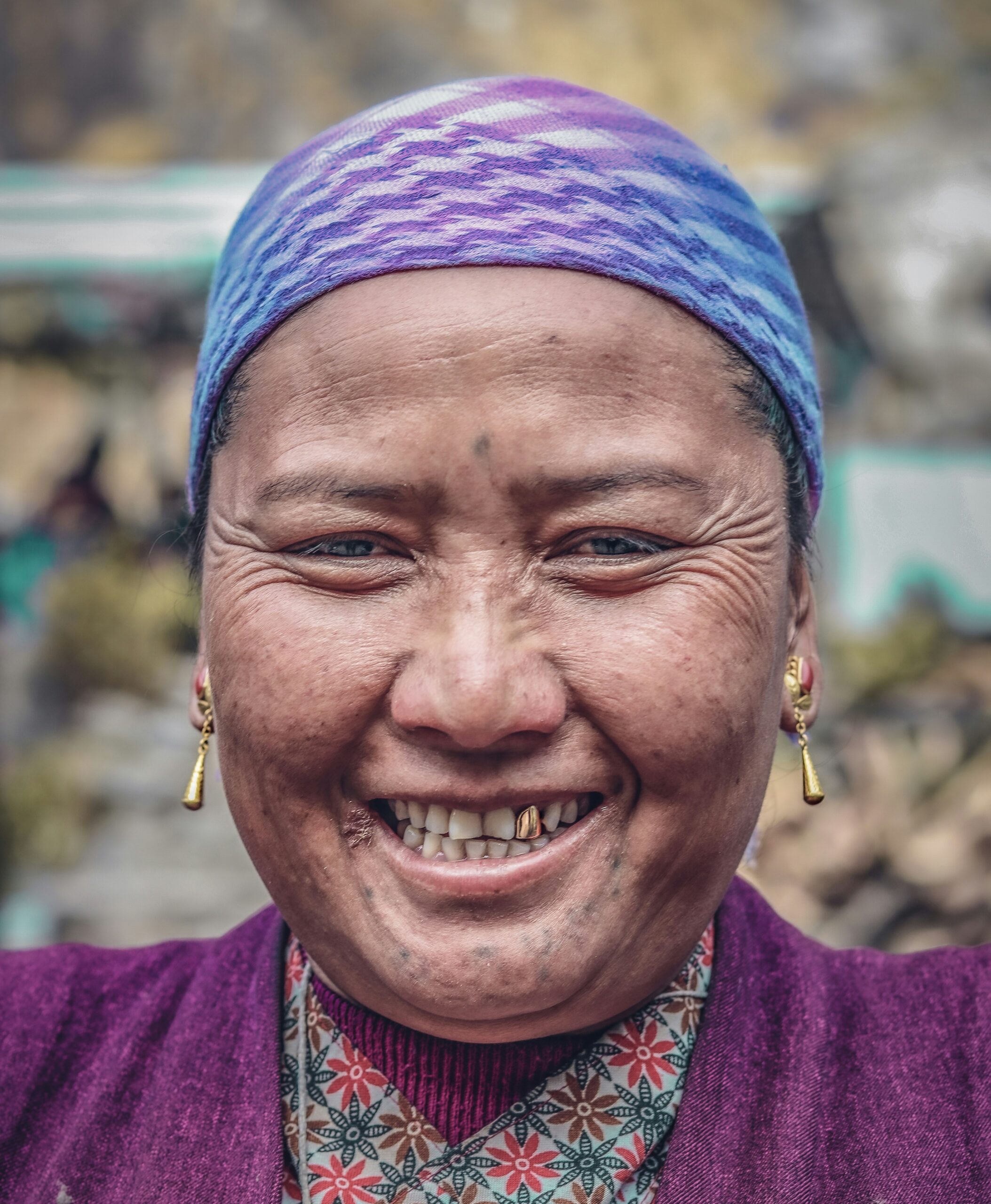 A smiling lady in purple clothes with a gold tooth.